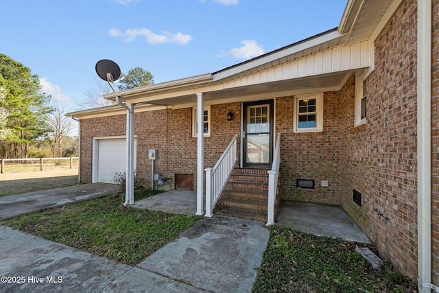 doorway to property with crawl space, concrete driveway, and brick siding