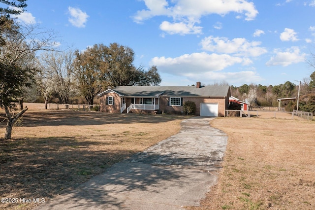 view of front facade featuring driveway, a porch, a front lawn, a garage, and brick siding