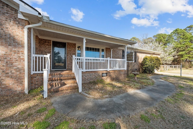 doorway to property with brick siding and a porch