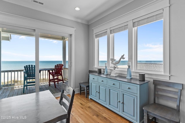 dining space featuring visible vents, crown molding, light wood-style floors, a water view, and recessed lighting
