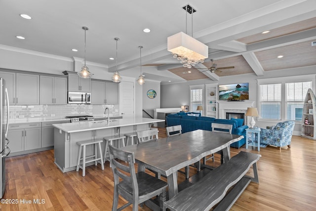 dining area with beamed ceiling, recessed lighting, ceiling fan, and a lit fireplace