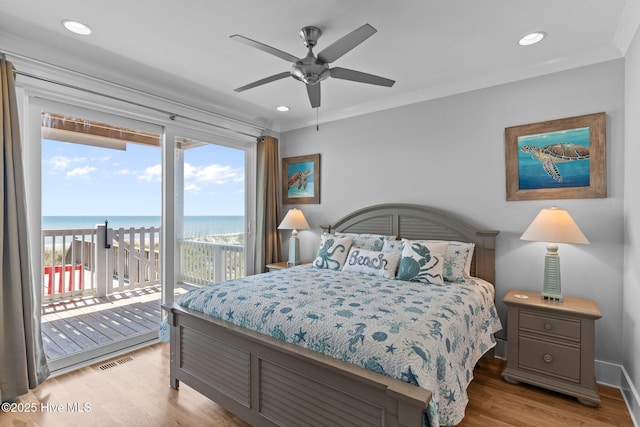 bedroom with a water view, access to exterior, light wood finished floors, and multiple windows