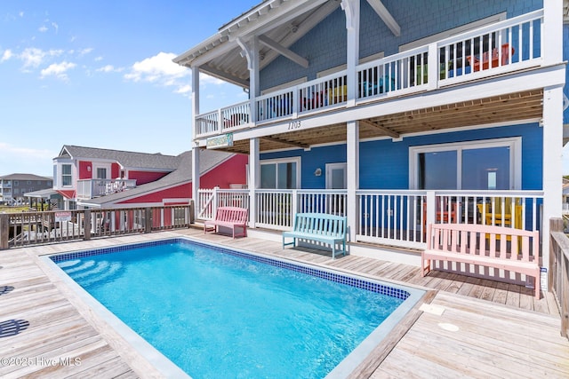 back of house featuring a wooden deck, an outdoor pool, and a balcony