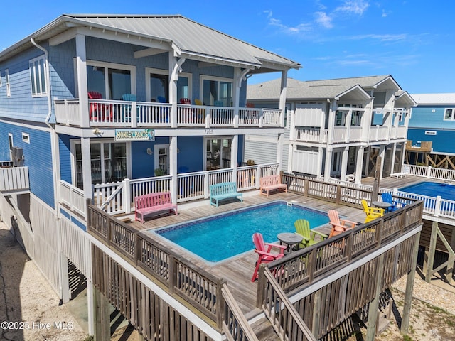 rear view of property featuring an outdoor pool and a wooden deck