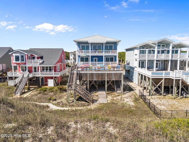 back of house with fence, stairway, a balcony, a standing seam roof, and metal roof