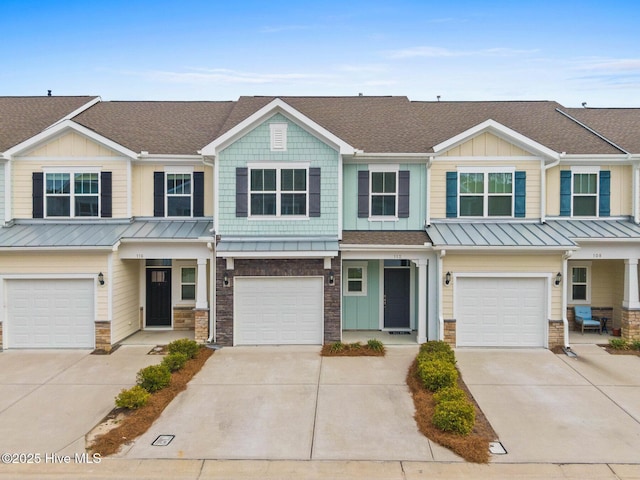 view of property featuring an attached garage, stone siding, driveway, and roof with shingles