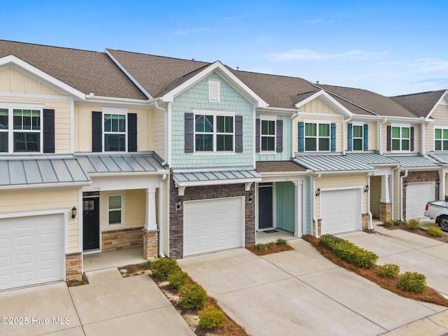 townhome / multi-family property with a garage, stone siding, driveway, and a shingled roof