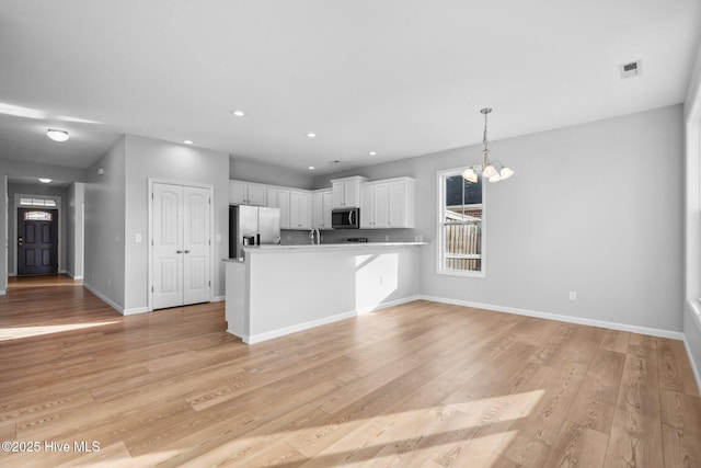 kitchen with visible vents, a chandelier, a peninsula, white cabinets, and stainless steel appliances