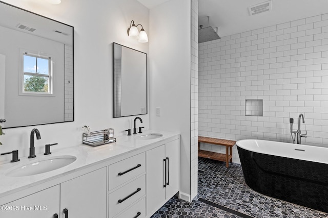 full bathroom with a sink, visible vents, a freestanding bath, and double vanity