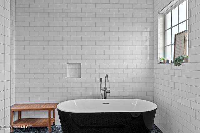 full bathroom featuring tile patterned flooring, tile walls, and a freestanding tub