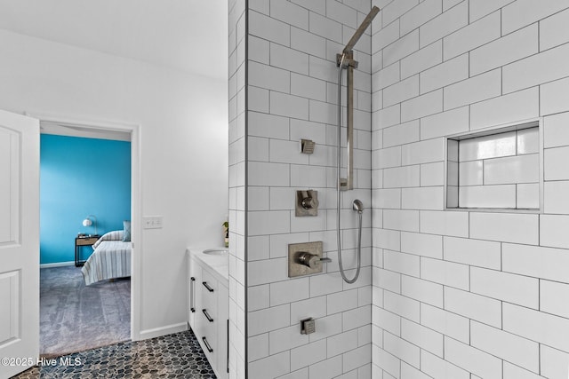 bathroom featuring baseboards, vanity, ensuite bathroom, and a tile shower