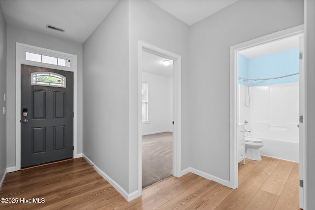 foyer with a wealth of natural light, visible vents, baseboards, and light wood-style floors