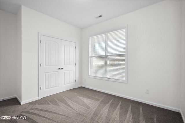 unfurnished bedroom featuring a closet, visible vents, baseboards, and carpet