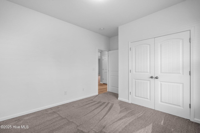 unfurnished bedroom with a closet, carpet floors, and baseboards