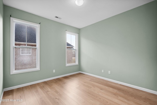 spare room featuring visible vents, baseboards, and wood finished floors