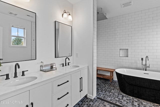 bathroom featuring a sink, visible vents, a soaking tub, and tile walls