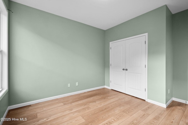 unfurnished bedroom featuring a closet, baseboards, and wood finished floors