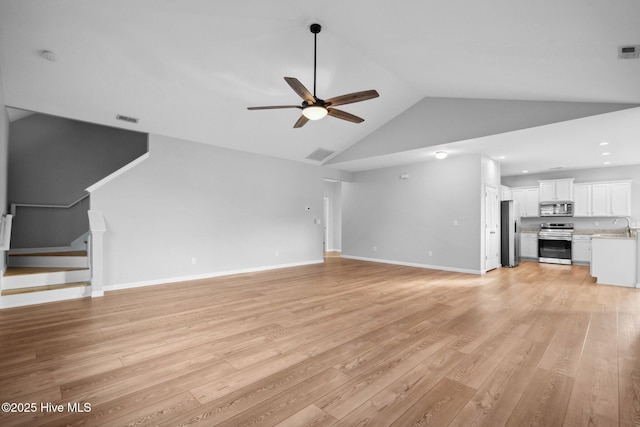 unfurnished living room with visible vents, baseboards, ceiling fan, light wood-type flooring, and a sink