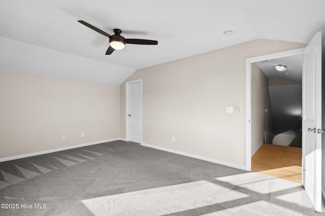 unfurnished bedroom featuring carpet floors, ceiling fan, baseboards, and vaulted ceiling