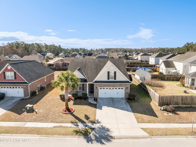 view of front of property featuring a garage, a residential view, driveway, and fence