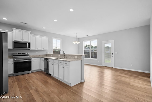 kitchen featuring a notable chandelier, a sink, stainless steel appliances, light wood-style floors, and white cabinets