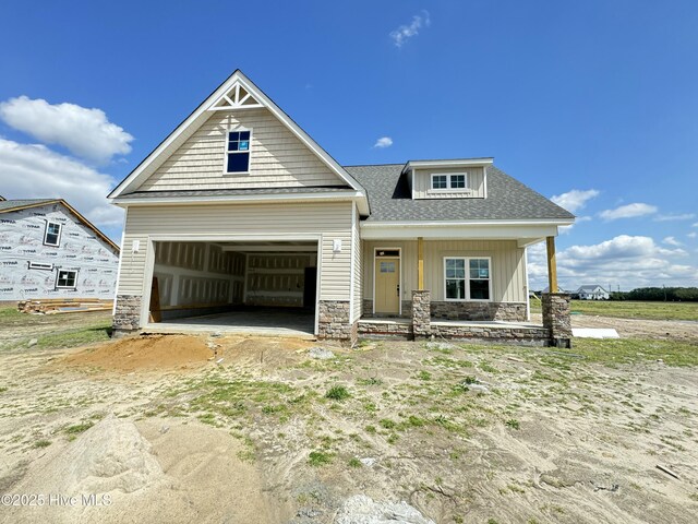 craftsman house featuring stone siding, board and batten siding, concrete driveway, an attached garage, and a front yard