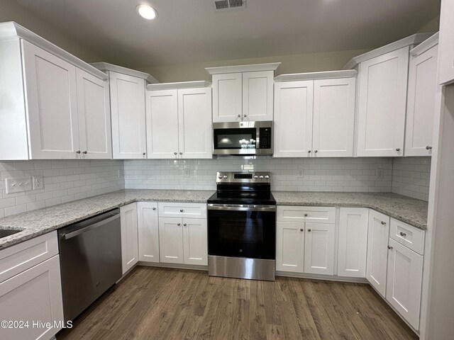 kitchen with a sink, stainless steel appliances, dark wood-style floors, and white cabinets