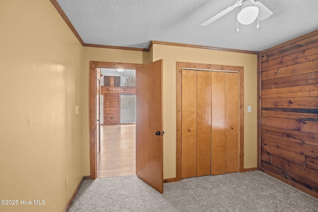 carpeted bedroom with crown molding, baseboards, a closet, a textured ceiling, and a ceiling fan