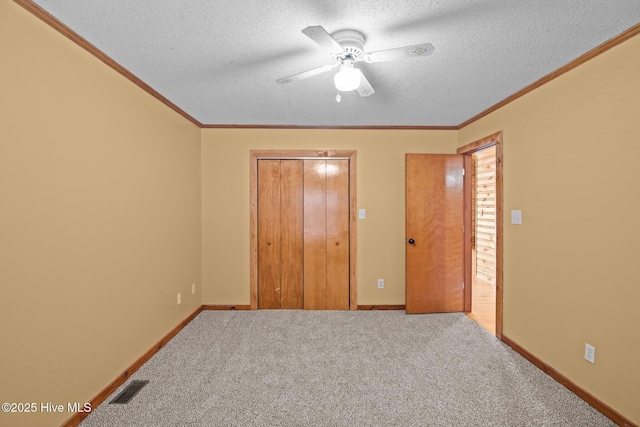 unfurnished bedroom with visible vents, ornamental molding, a closet, a textured ceiling, and carpet flooring