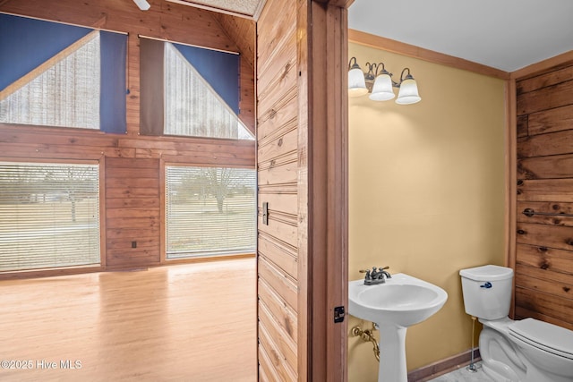 bathroom featuring wooden walls, toilet, and wood finished floors