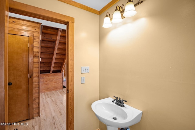 bathroom with a sink, wood finished floors, and crown molding