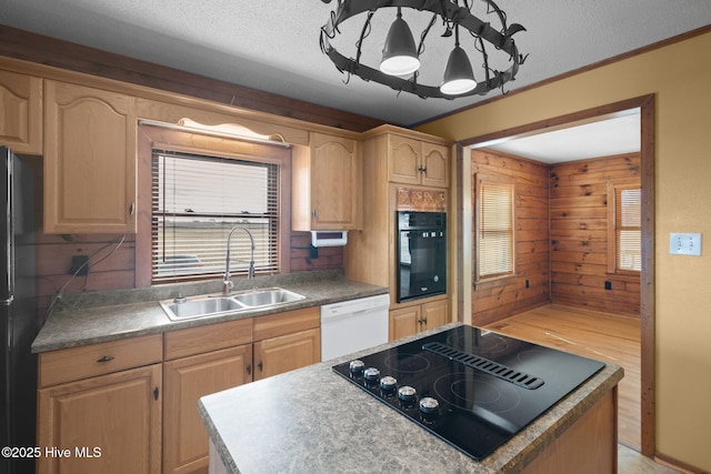 kitchen with a center island, wood walls, plenty of natural light, black appliances, and a sink