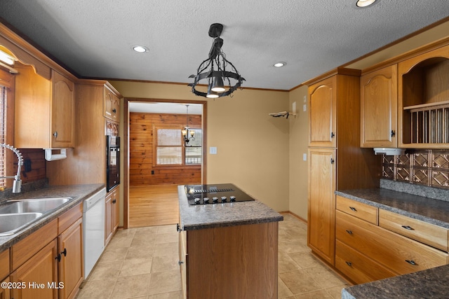 kitchen featuring black appliances, a sink, dark countertops, a kitchen island, and a textured ceiling