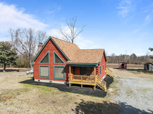 log home featuring a shingled roof, a front lawn, log siding, a chimney, and an outdoor structure