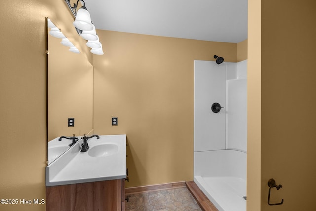 full bath featuring vanity, baseboards, and a stall shower