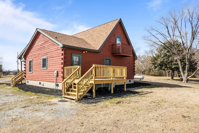 rear view of house featuring a shingled roof, a balcony, log siding, and crawl space