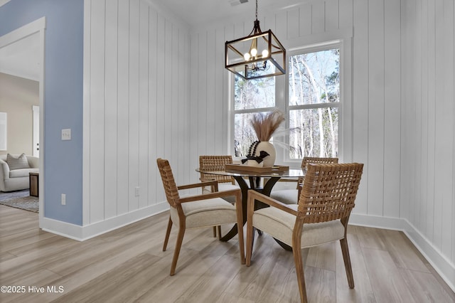 dining space with a chandelier, baseboards, visible vents, and light wood-style flooring