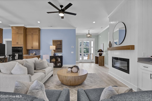 living room with light wood-type flooring, baseboards, ornamental molding, and a fireplace