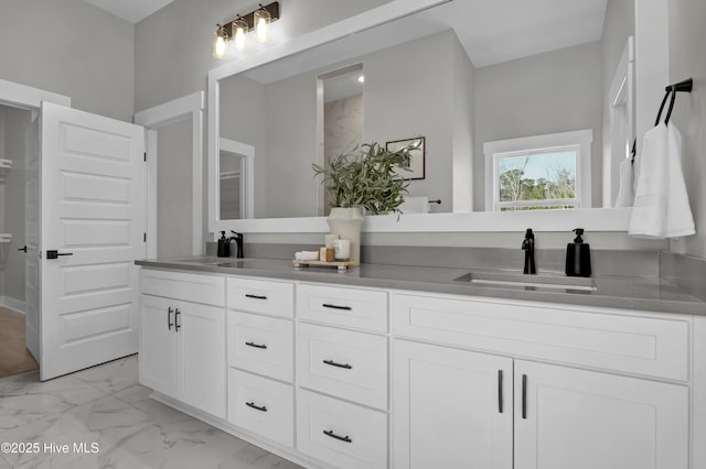 full bath featuring a sink, marble finish floor, and double vanity