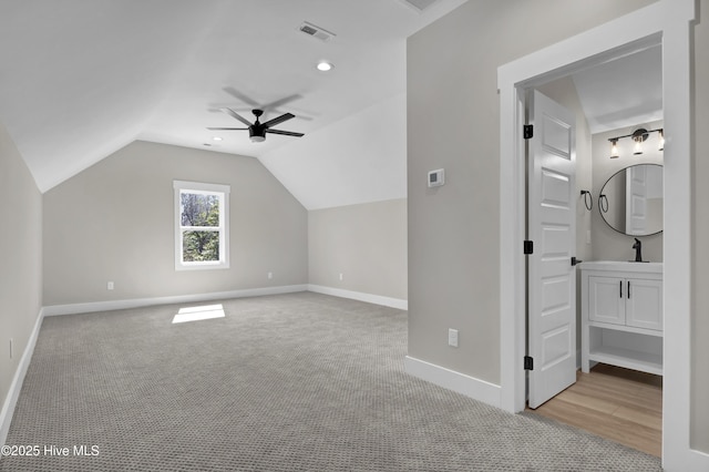 additional living space with visible vents, baseboards, light colored carpet, vaulted ceiling, and a ceiling fan