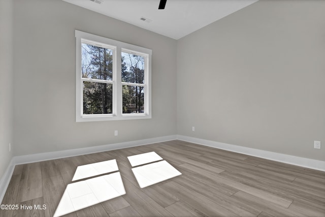 empty room with visible vents, a ceiling fan, baseboards, and wood finished floors