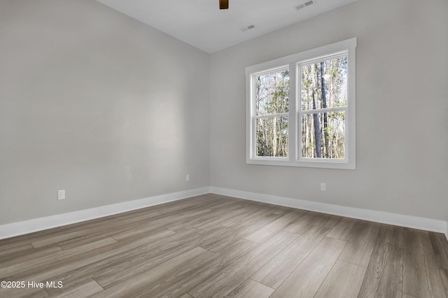 unfurnished room featuring a ceiling fan, visible vents, wood finished floors, and baseboards