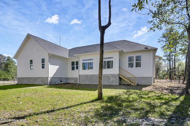 back of property with a lawn and fence