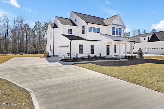 modern farmhouse style home with metal roof, an attached garage, concrete driveway, and a front yard