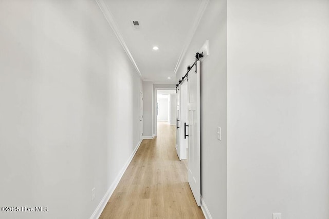 hallway with ornamental molding, recessed lighting, a barn door, light wood finished floors, and baseboards