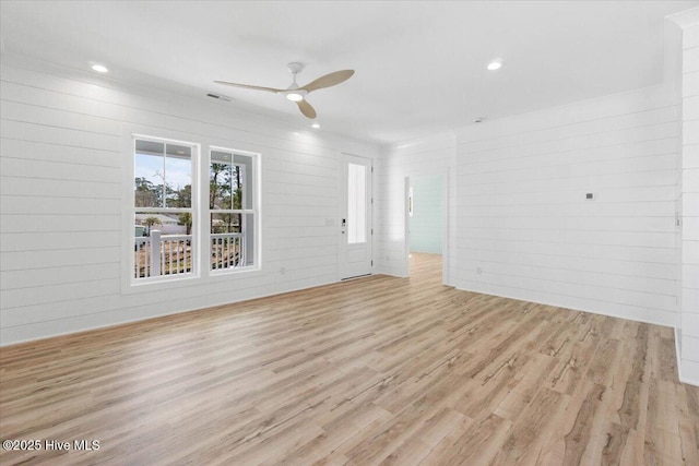 spare room featuring recessed lighting, light wood-style flooring, a ceiling fan, and wood walls