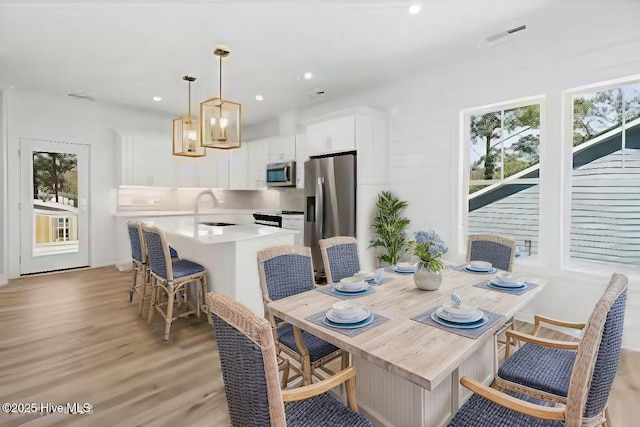 dining space featuring light wood-type flooring, recessed lighting, and a healthy amount of sunlight