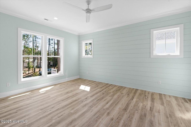 spare room featuring visible vents, crown molding, baseboards, wood finished floors, and a ceiling fan