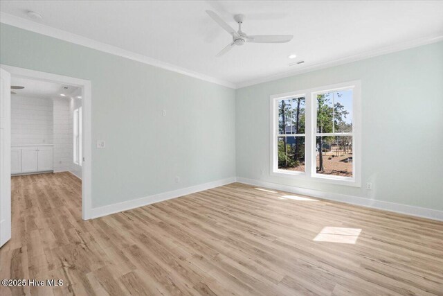 spare room featuring light wood finished floors, baseboards, and ornamental molding