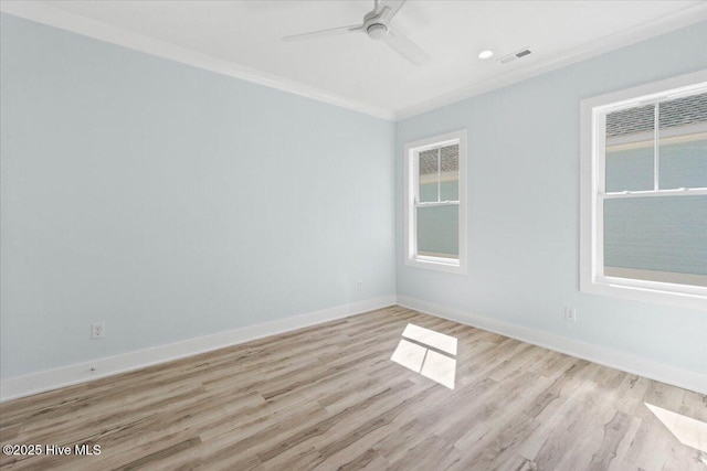 empty room with light wood-style flooring, ornamental molding, baseboards, visible vents, and a ceiling fan